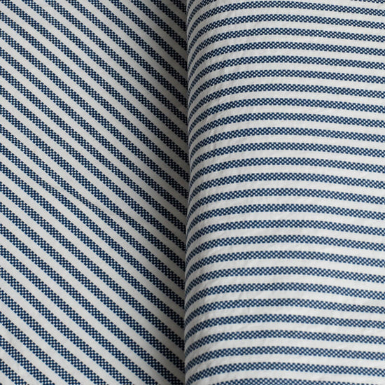 Close-up of fabric with blue and white striped pattern. 100% Organic percale cotton bed sheets. 
