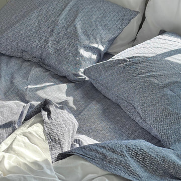 Blue textured bedding on a bed with white pillows. 100% Organic percale cotton bed sheets. 