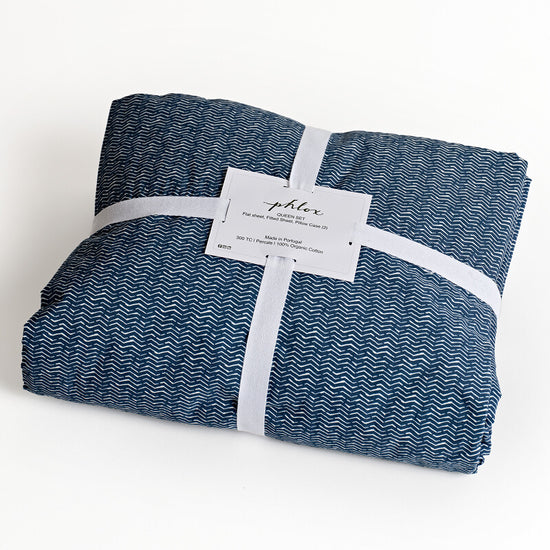 Folded blue and white patterned fabric with a label on a light background. 100% Organic percale cotton bed sheets. 