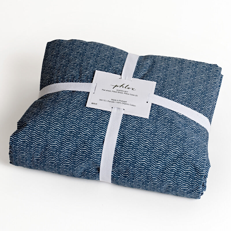 Folded blue and white patterned fabric with a label on a light background. 100% Organic percale cotton bed sheets. 