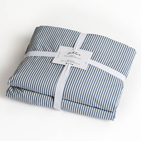 Folded blue and white striped fabric with a label on a white background. 100% Organic percale cotton bed sheets. young boy bed sheets