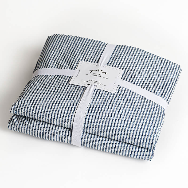 Folded blue and white striped fabric with a label on a white background. 100% Organic percale cotton bed sheets. young boy bed sheets
